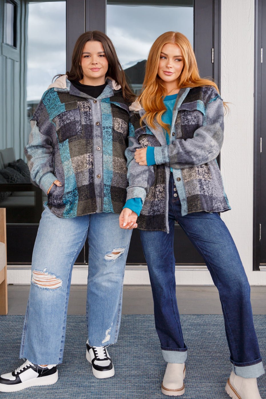 Two models wearing plaid shackets with removable fleece hoods, standing together.