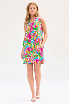 Woman wearing a sleeveless, multicolored geometric patterned dress with a mandarin collar and pleated detail on the back.