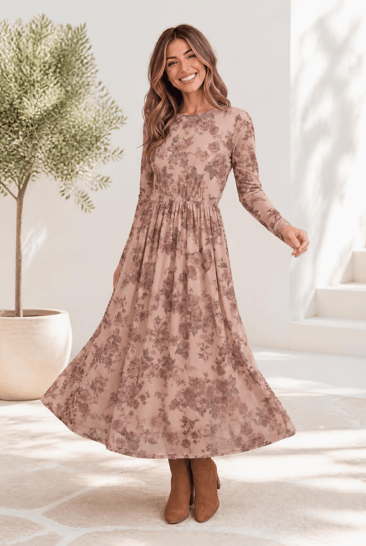 A woman wearing a blush midi dress with dusty rose floral print, long sleeves, and a flowing skirt.