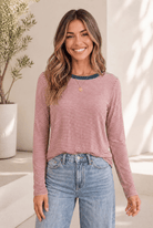 Red long sleeve tee with horizontal stripes and teal neckline, worn by a model with light jeans.