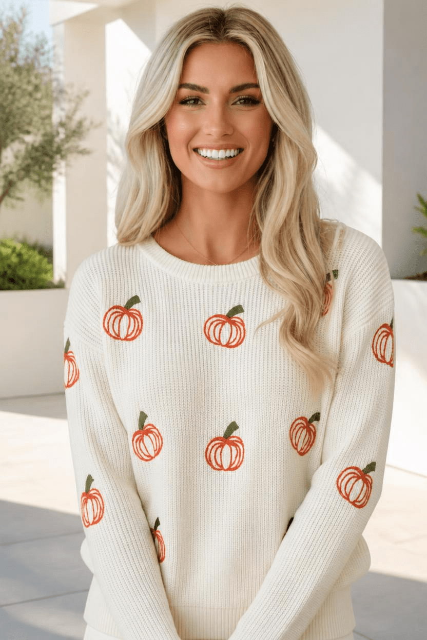 Cream ribbed knit sweater with pumpkin embroidery worn by a smiling woman.