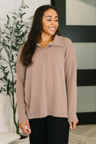 A high-stretch, cable ribbed knit pullover in a neutral color with a collared design and drop shoulder.