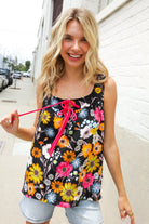 Woman wearing a colorful floral tank top on a city street.