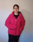 A woman wearing a vibrant pink quilted puffer jacket with a mock neck and zip closure.