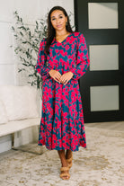 A woman wearing a multicolor floral V-neck dress with long sleeves and an elastic waistband.