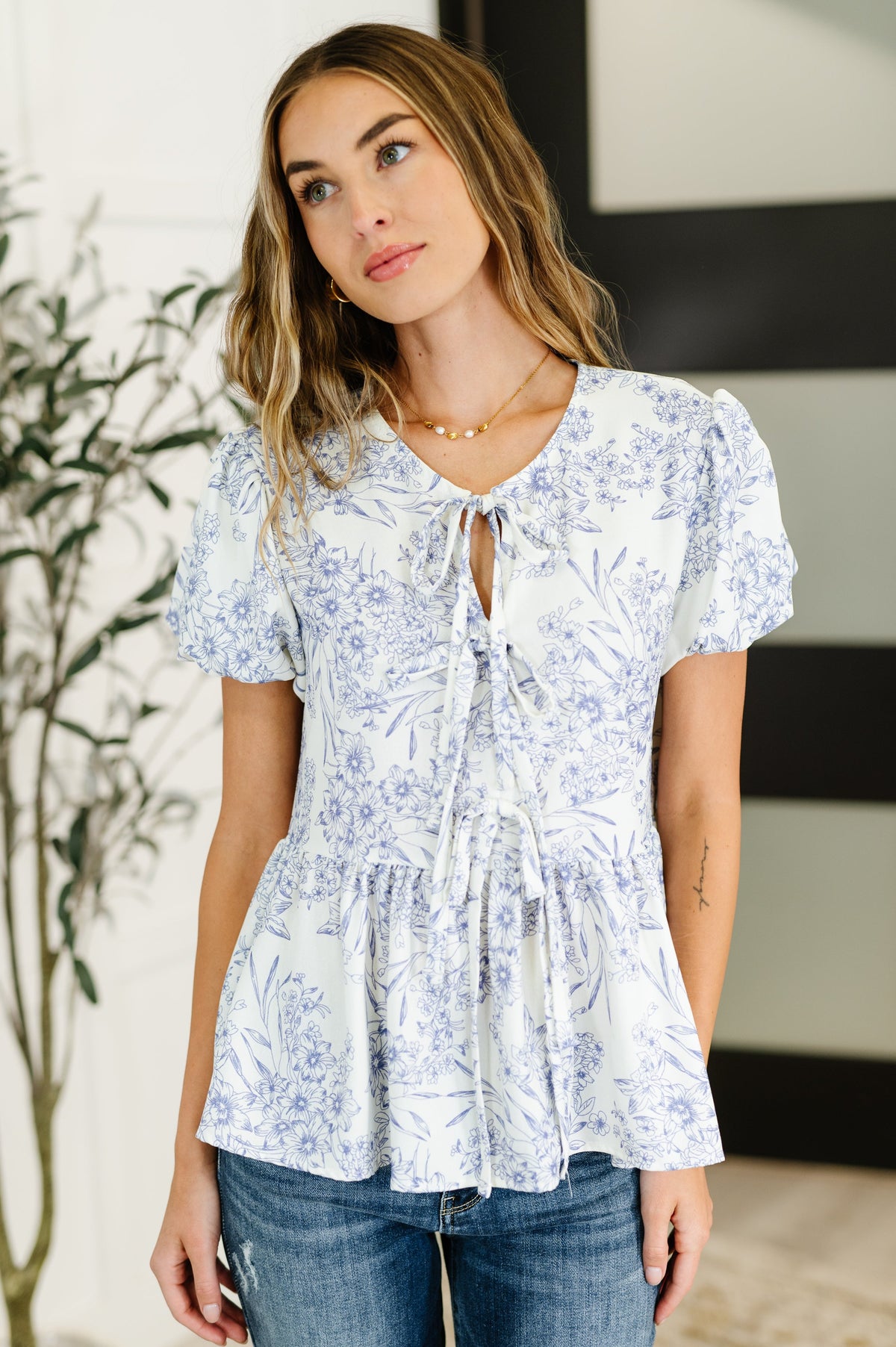 Woman wearing a white floral blouse with a blurred indoor background