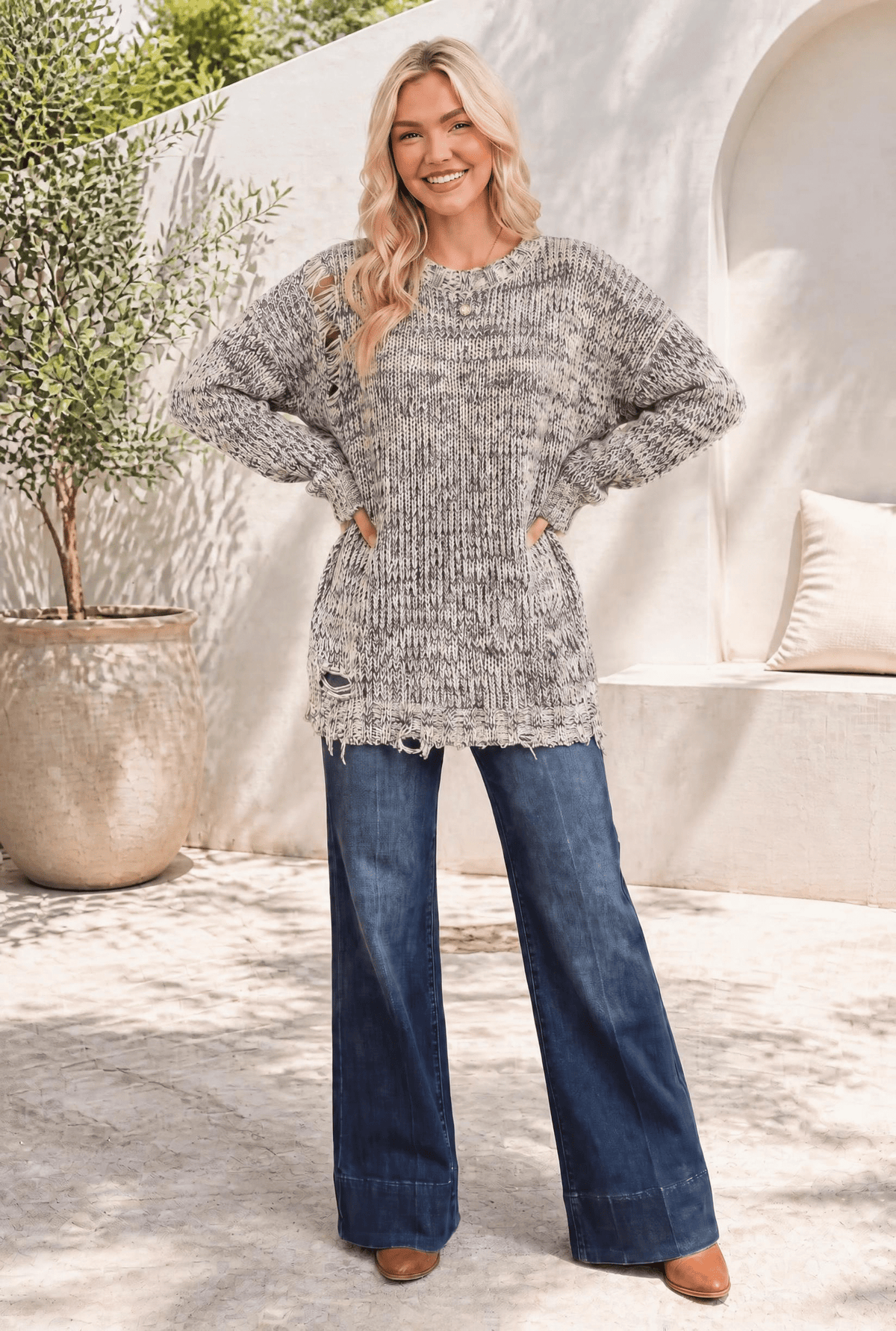 Model wearing a relaxed, marled purple and cream knit sweater with distressed fringe trim.