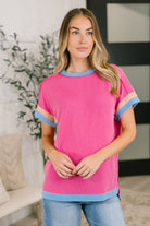 Pink textured contrast top with blue banded round neckline and cuffs, featuring a relaxed fit and dolman sleeves.