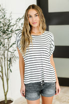 Woman wearing a black and white striped shirt and denim shorts indoors.