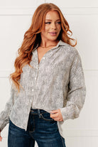 Woman wearing a patterned shirt and jeans against a white background